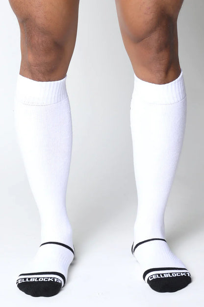 White knee-high socks with black trim and ribbed texture featuring cellblock 13 branding on the heel back view