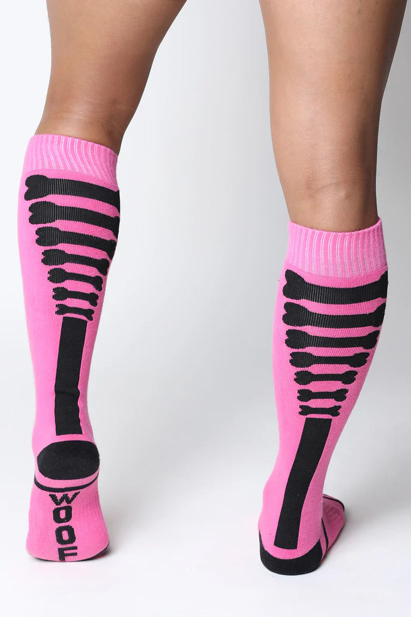 Pink knee high wool socks with black skeletal bone patterns and wool printed on the heel from kennel club bones collection