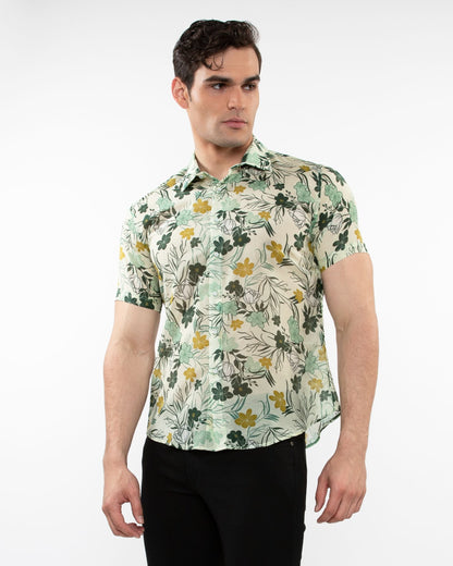 A man wearing a lightweight cotton silk short-sleeved shirt with green yellow floral pattern on off-white background