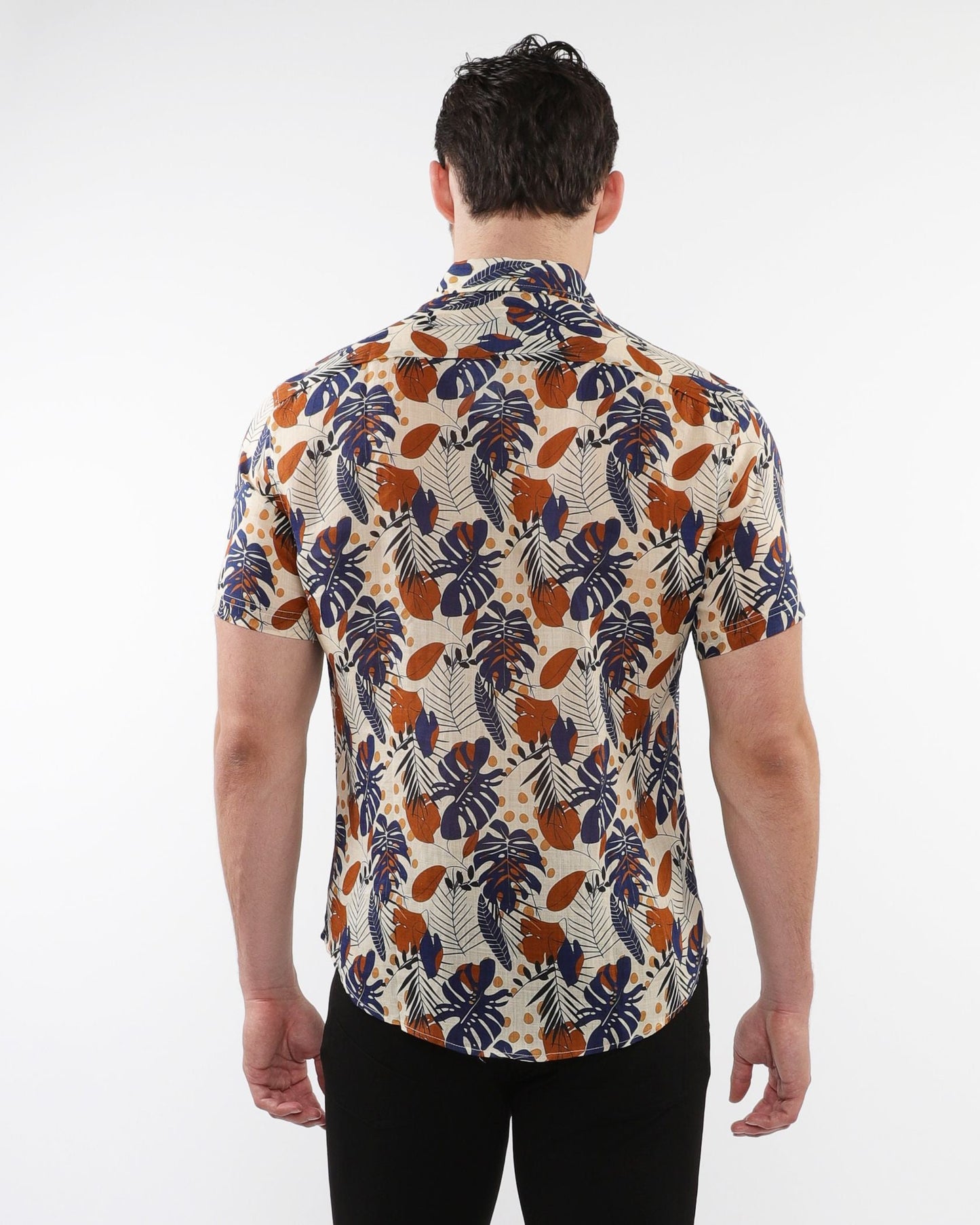A man wearing a lightweight linen tencel short-sleeved shirt with a tropical leaf and fruit pattern on beige