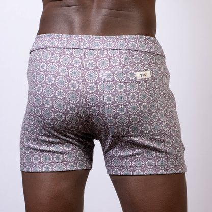 Back side of gray and white mandala linen texture shorts with a circular pattern and brand tag on the waistband