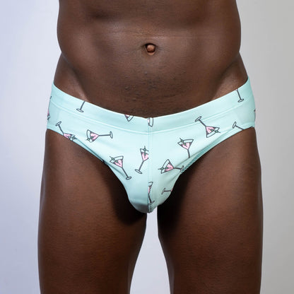 Mint green martini swim brief with playful pink martini glass pattern and black outlines perfect for swimming