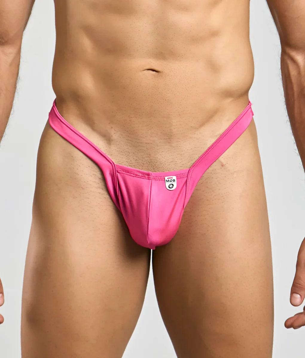 Bright pink sleek form-fitting mob y buns thong made from smooth stretch fabric with small white brand tag at center back