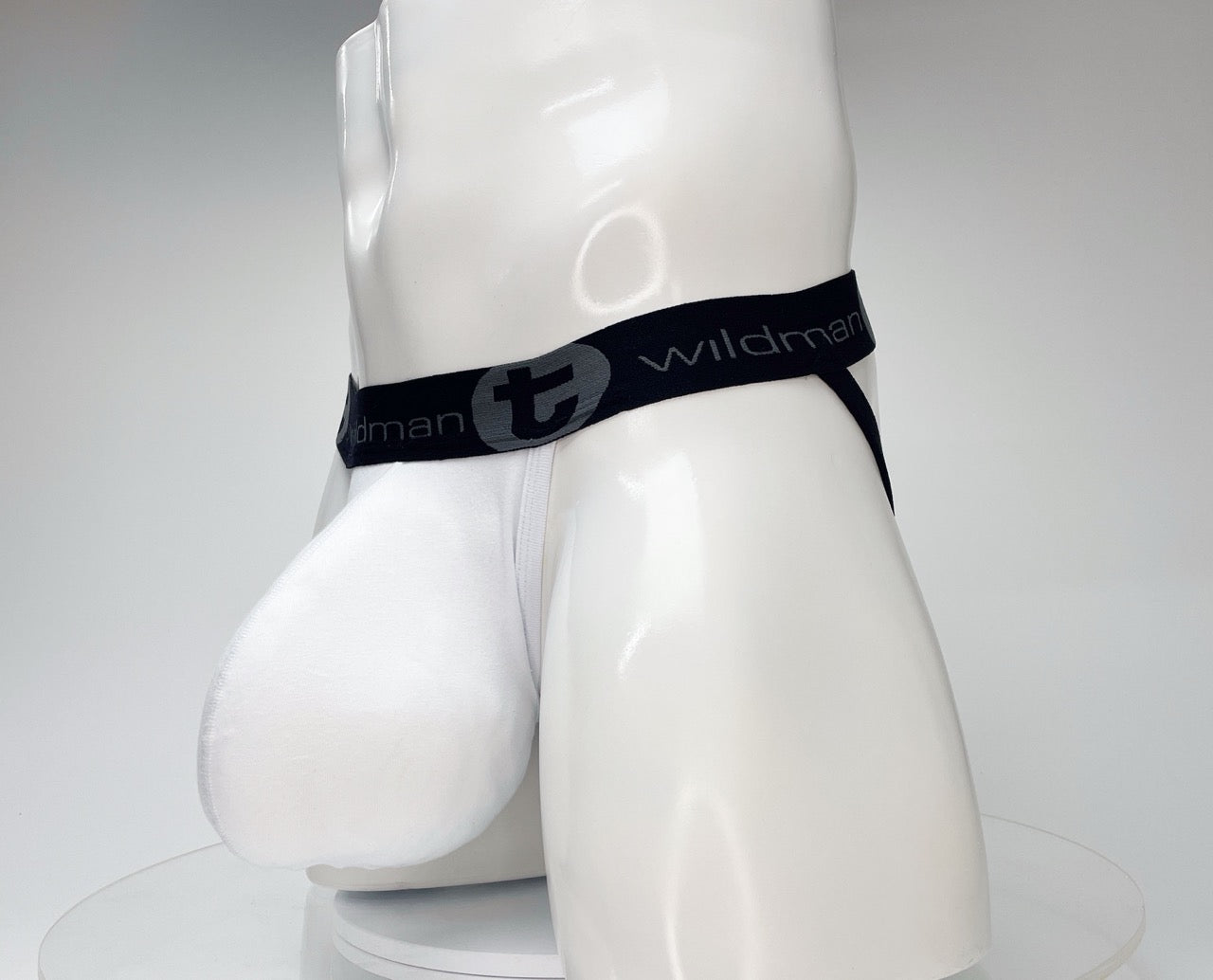 White jockstrap on a mannequin with a large contoured pouch and a black waistband featuring the WildmanT logo.