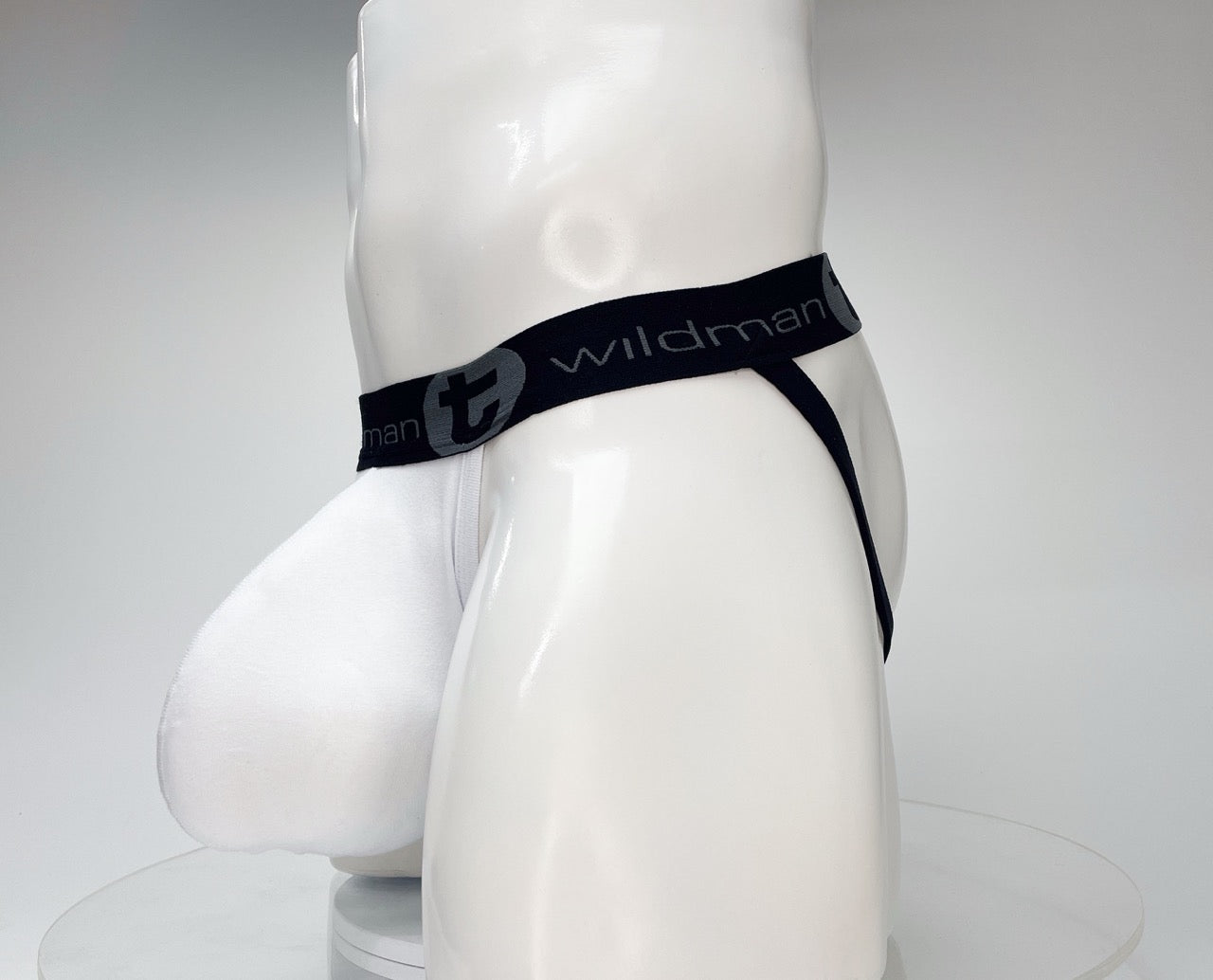White WildmanT jockstrap with a large, contoured front pouch and a black branded elastic waistband on a mannequin.