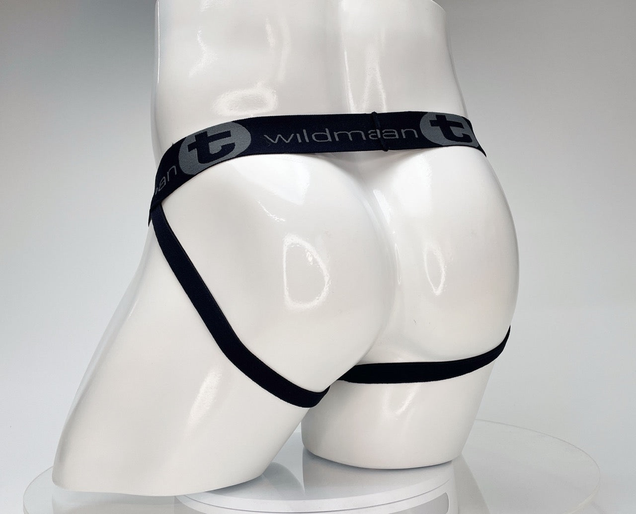 White WildmanT jockstrap on a mannequin, featuring a black branded elastic waistband and thin leg straps.