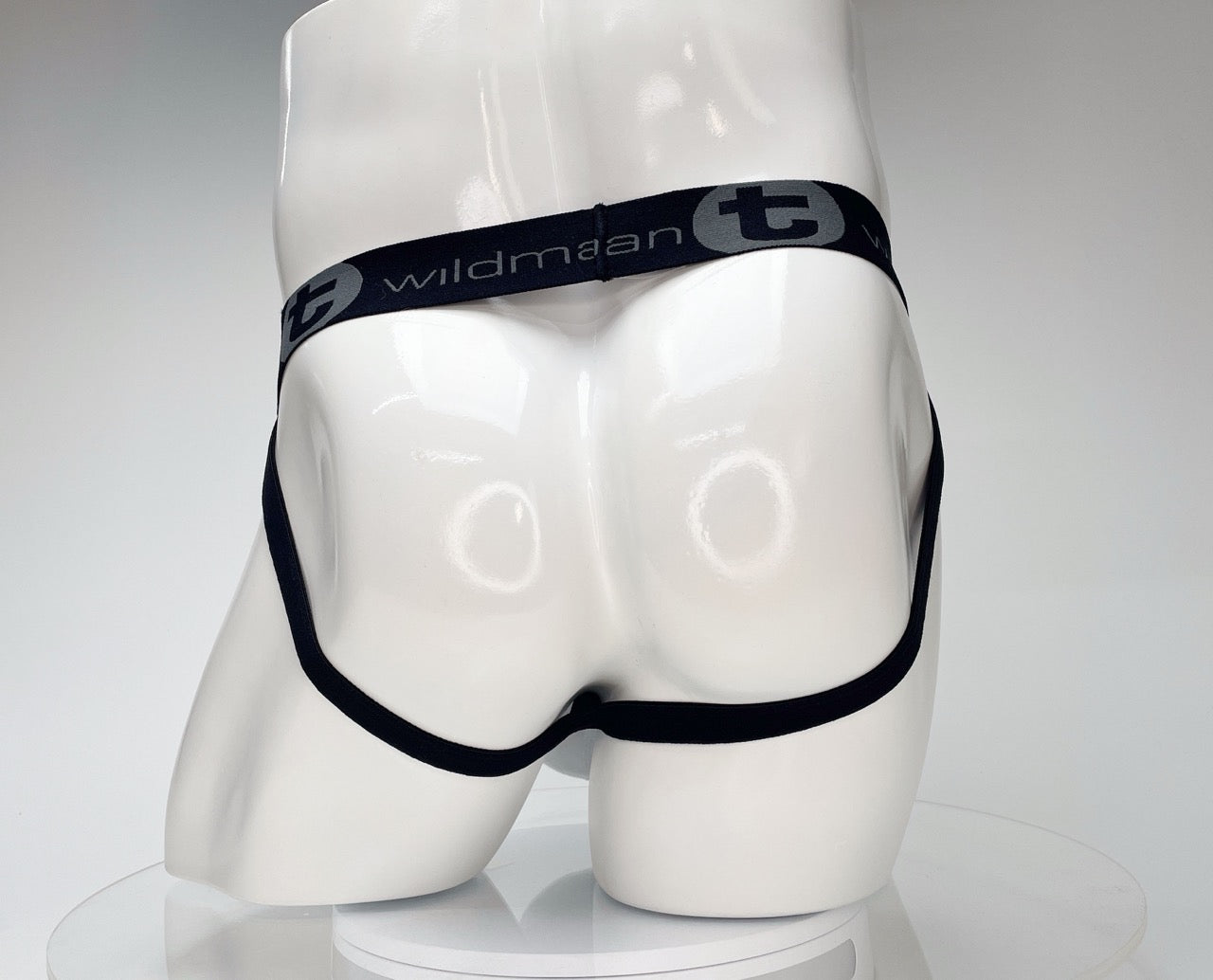 White jockstrap on a mannequin, featuring a black elastic waistband with the grey WildmanT logo and brand name.