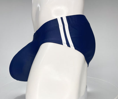 Navy WildmanT swim brief with white side stripes, featuring a contoured pouch design on a mannequin.