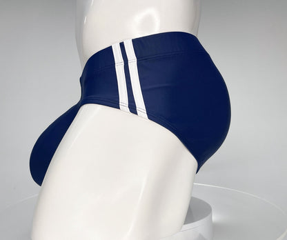 Navy blue WildmanT swim brief with two vertical white side stripes on a white mannequin.