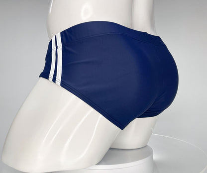 Navy blue WildmanT swim brief on a mannequin, featuring two white vertical stripes on the side.