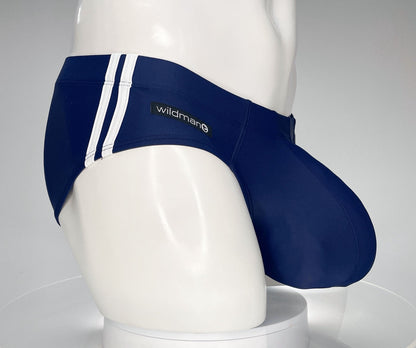 Navy blue WildmanT swim brief with white side stripes and a prominent contoured pouch on a white mannequin torso.
