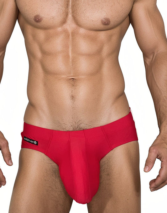 Red WildmanT swim brief with a contoured pouch and black logo tag on the hip, worn by a muscular man.