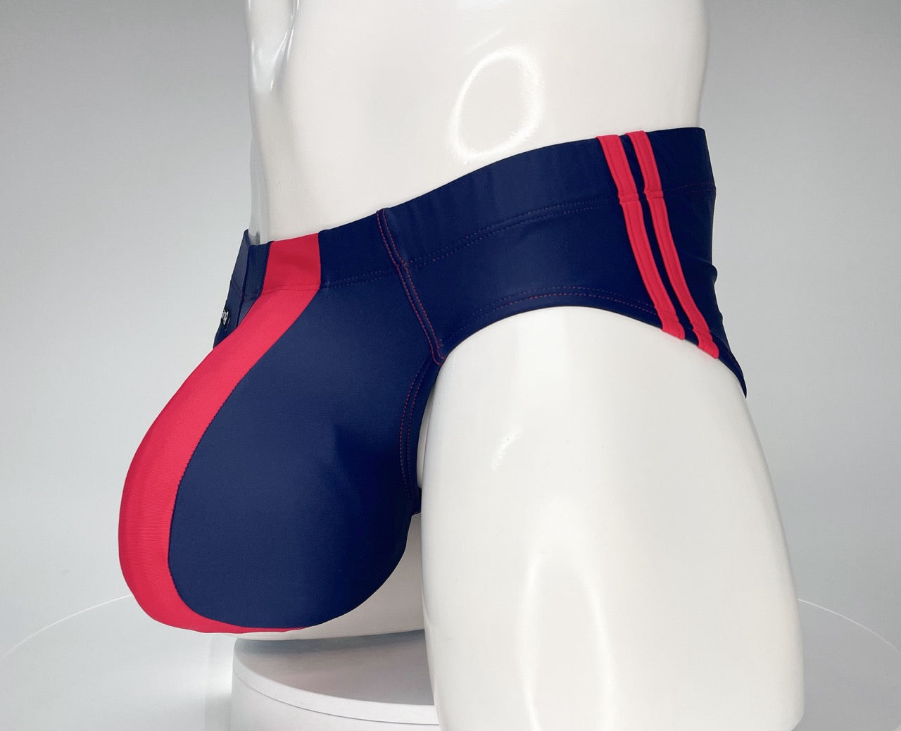 WildmanT navy and red swim brief with a contoured pouch, featuring side red stripes on a white mannequin.