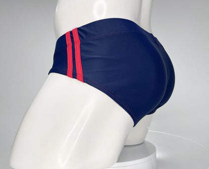 Navy blue swim brief with two red side stripes on a white mannequin.