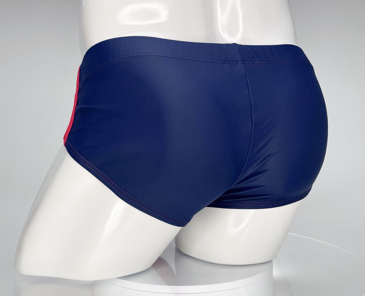 Navy blue WildmanT swim brief with red side stripes and red contrast stitching, shown on a white mannequin.