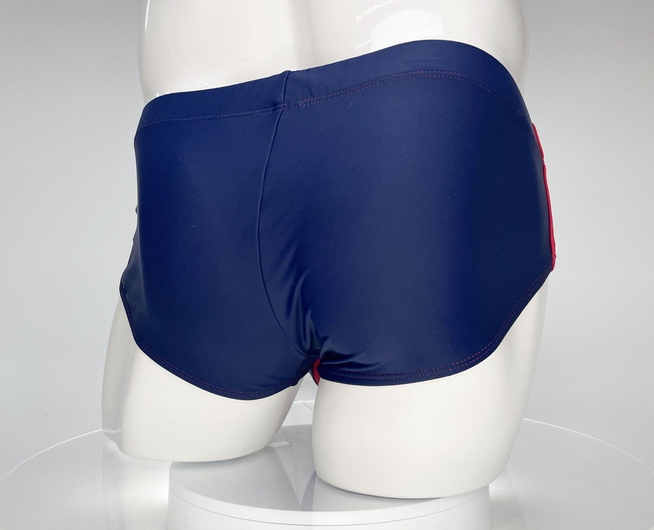 WildmanT navy blue swim brief with red side stripes and stitching, displayed on a white mannequin.