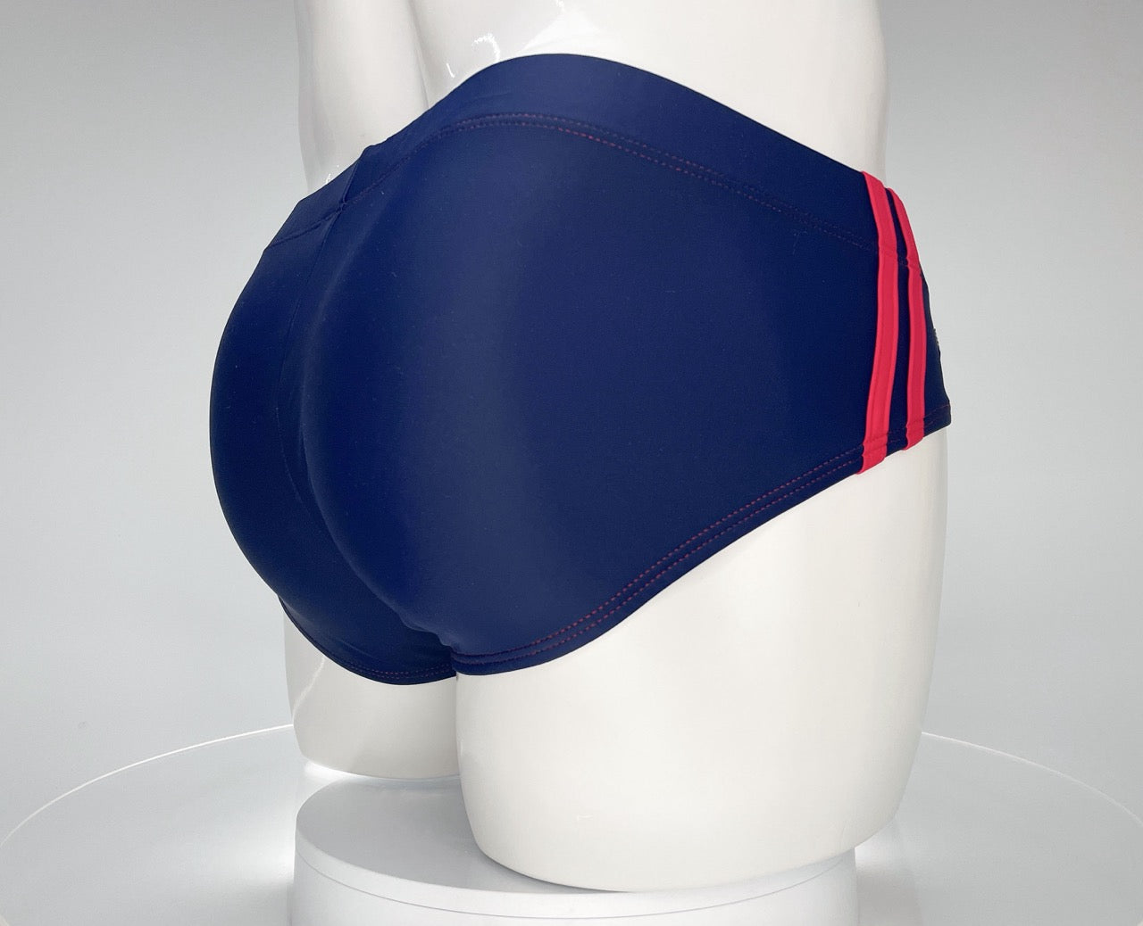 Navy blue WildmanT swim brief with red side stripes and red contrast stitching, shown on a white mannequin.