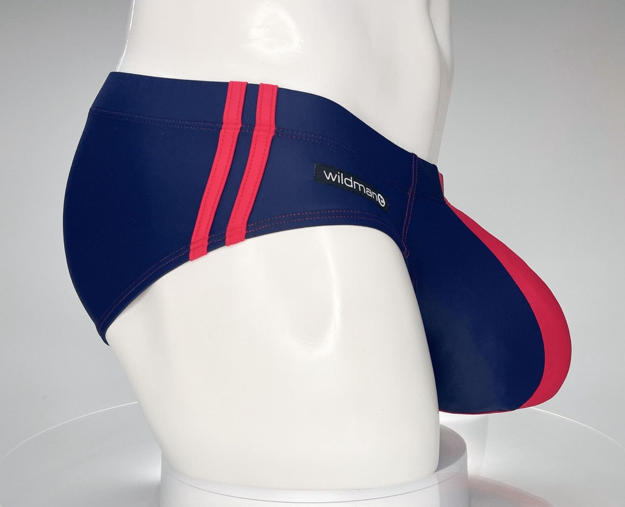Navy and red WildmanT swim brief with side stripe detail and a contoured pouch on a white mannequin.