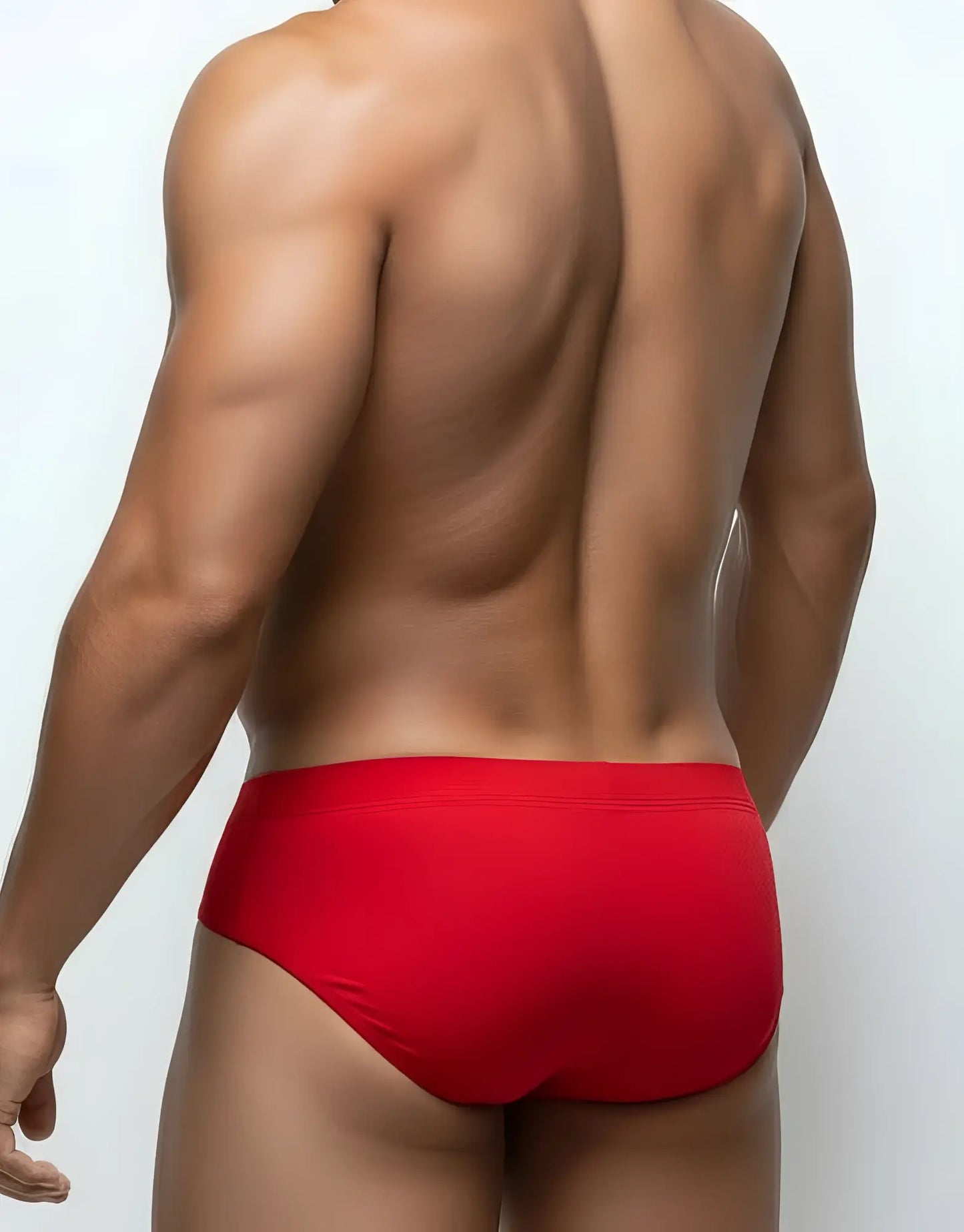 Back view of a muscular man wearing red Big Boy Pouch mesh briefs against a white background.