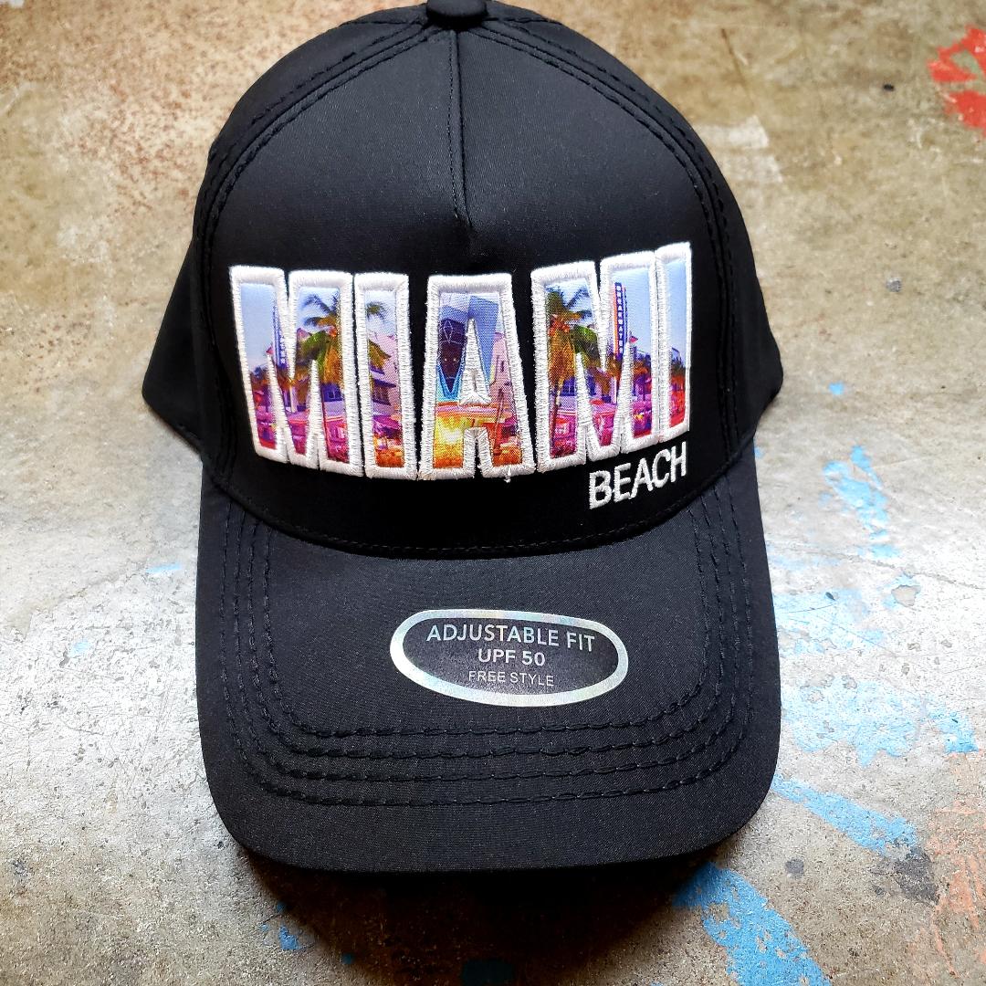 Black trucker hat featuring colorful embroidered miami design with palm trees and cityscape in vibrant hues