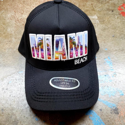 Black trucker hat featuring colorful embroidered miami design with palm trees and cityscape in vibrant hues