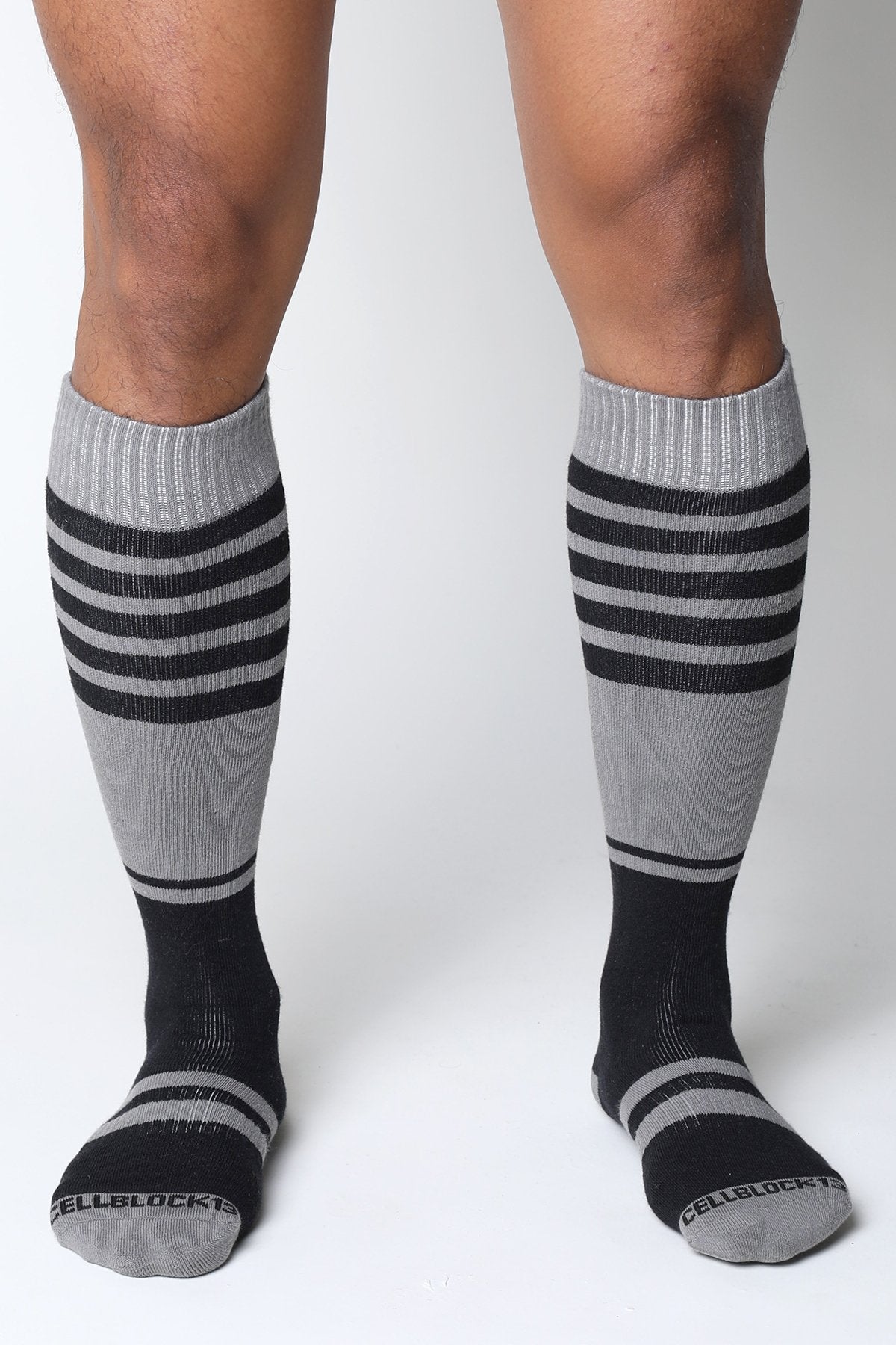 Gray and black striped midfield knee high socks with ribbed cuff and cellblock brand name on the toe