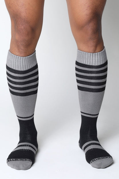 Gray and black striped midfield knee high socks with ribbed cuff and cellblock brand name on the toe