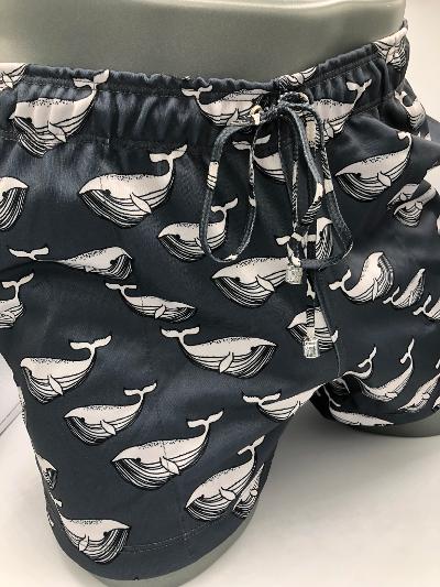 Black moby dick shorts with repeating white whale line art pattern made for swimwear use