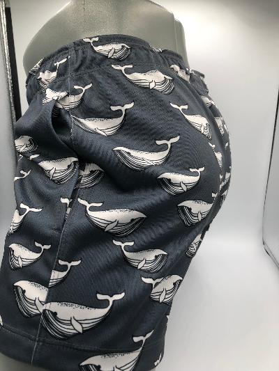 Dark gray moby dick shorts with a repeating white whale pattern ideal for swimwear and beach use