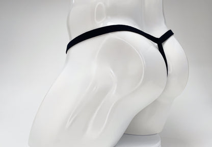 Black thong on a white mannequin torso, seen from behind.