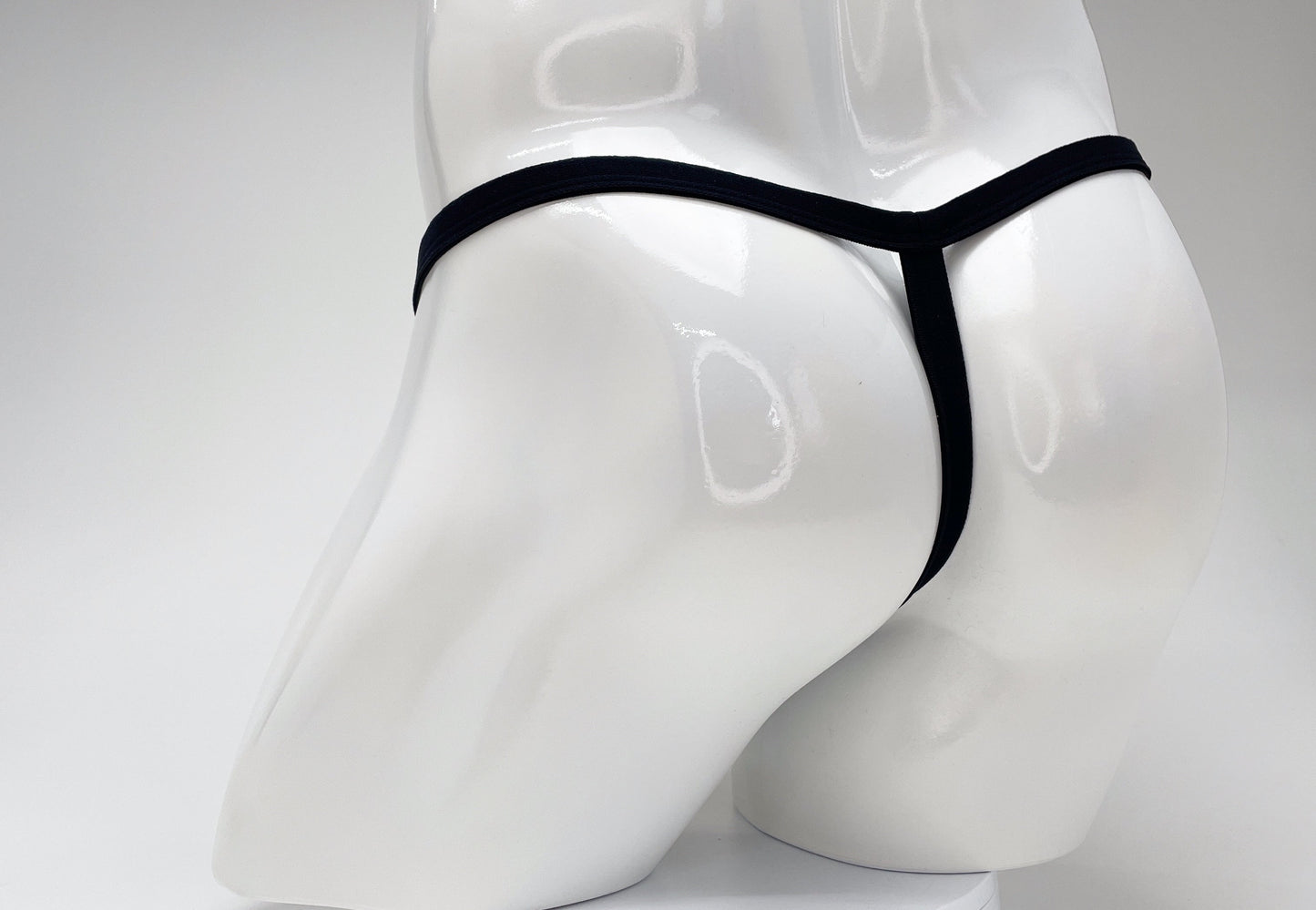 WildmanT modal micro thong in black, worn on a glossy white male mannequin, shown from the back view.