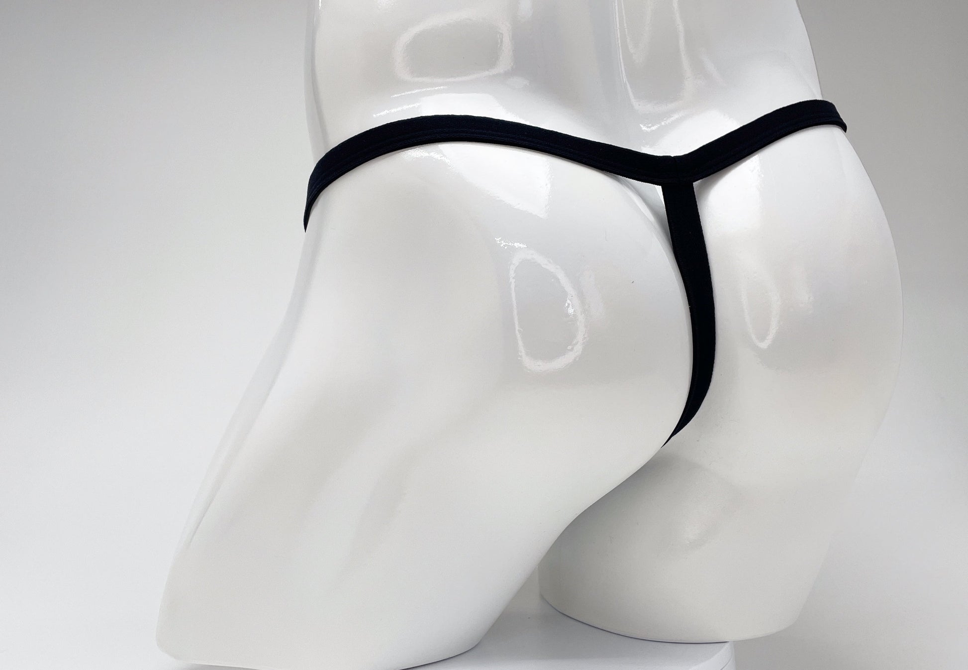 WildmanT modal micro thong in black, worn on a glossy white male mannequin, shown from the back view.