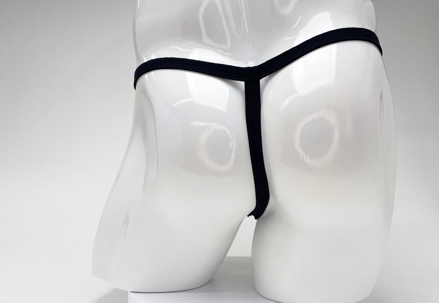 Back view of a white male mannequin wearing a minimalist black WildmanT modal micro thong.
