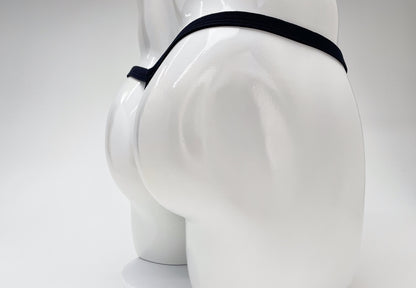 Back view of a white mannequin wearing a minimal black thong with a thin waistband against a white background.