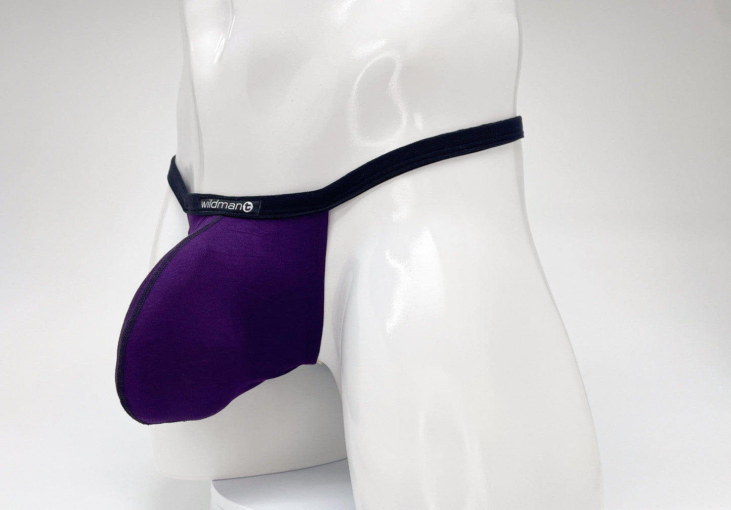 Purple WildmanT modal micro thong with a prominent pouch, black trim, and a branded logo tag on a white mannequin.