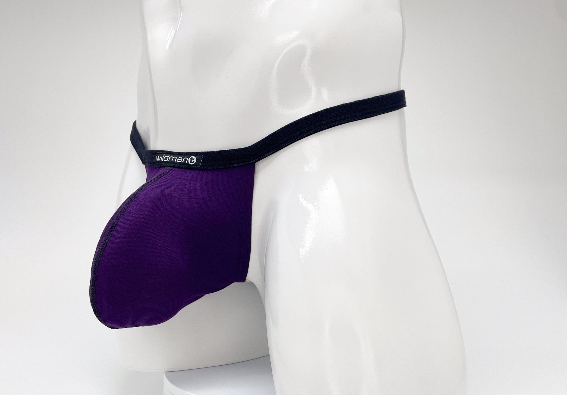 Purple WildmanT modal micro thong with a prominent pouch, black trim, and a branded logo tag on a white mannequin.