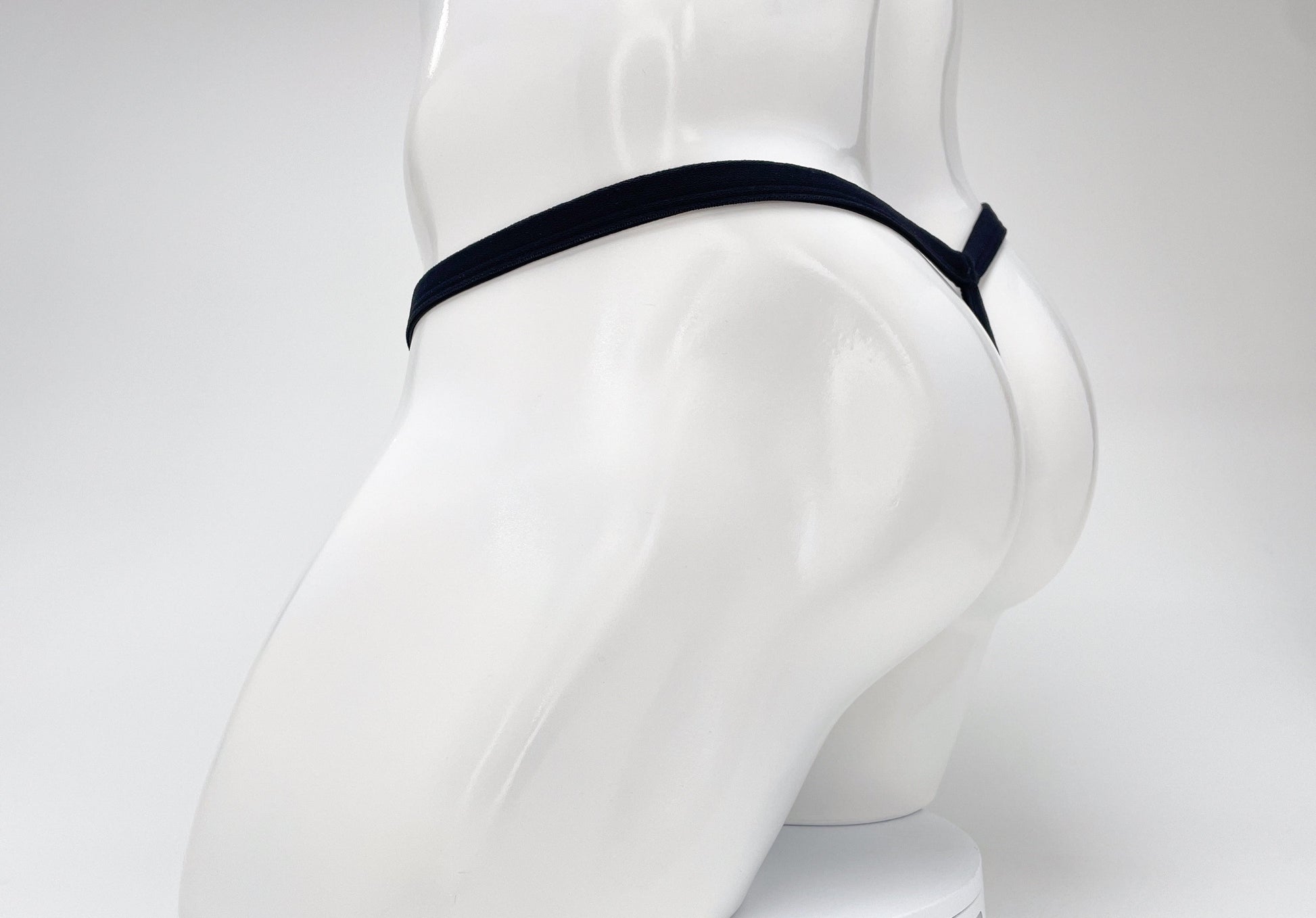 A dark purple WildmanT modal micro thong on a white mannequin, showing the rear T-back style.