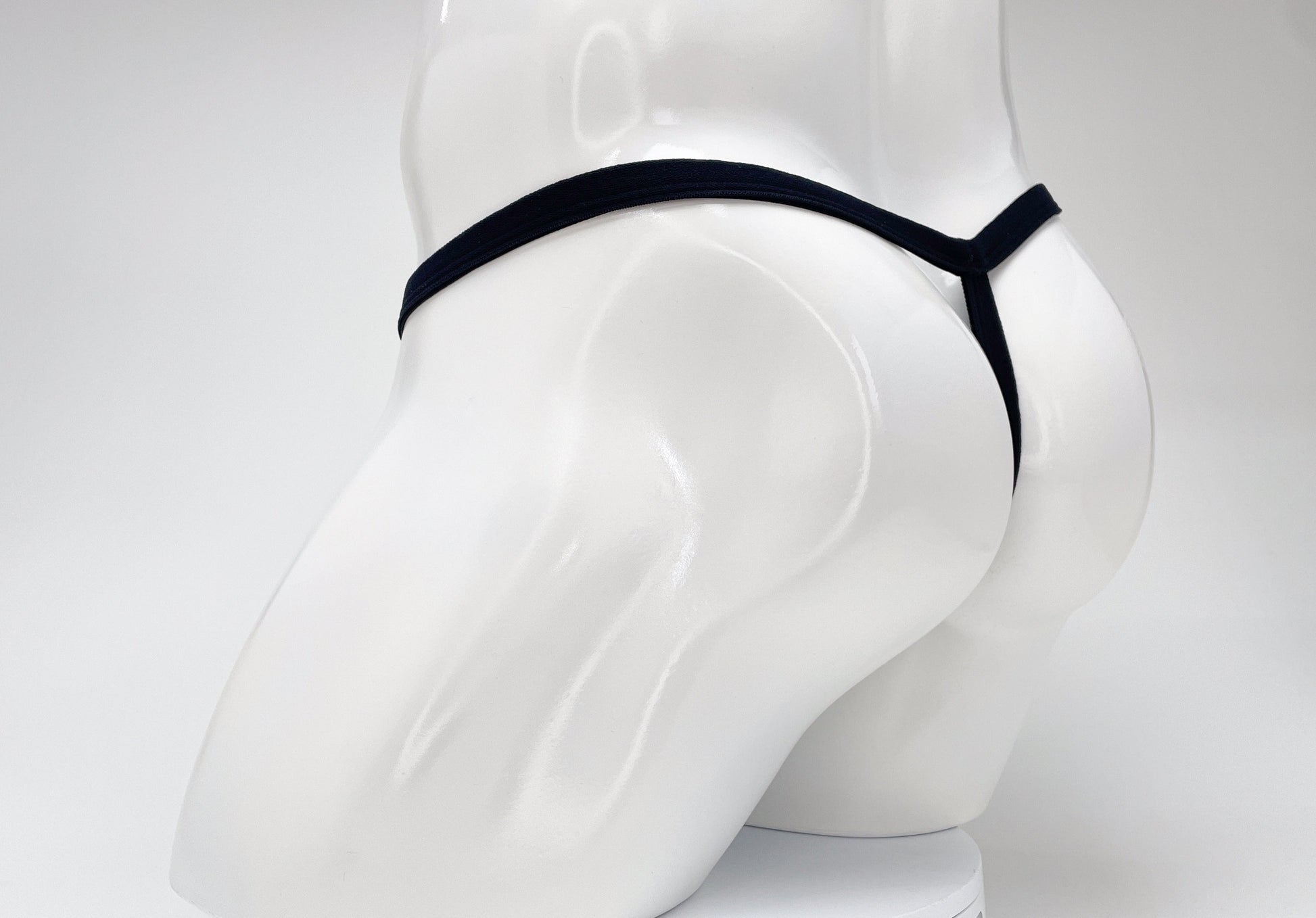 Purple WildmanT micro thong with a thin waistband and minimalist rear coverage on a white mannequin.