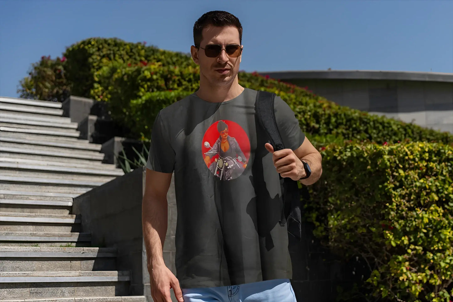 Dark gray short-sleeved t-shirt featuring a circular graphic of a man on a motorcycle on a red background