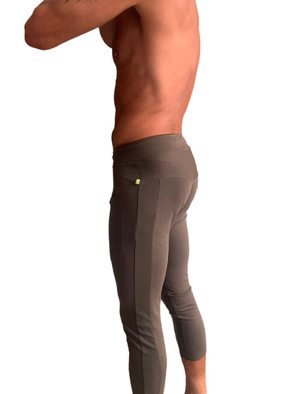 Dark gray form-fitting mens capri yoga pants with textured side panel and yellow tag shown from the back side
