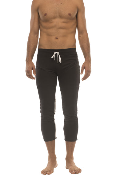 Mens black capri yoga pants with white drawstring waistband and subtle charcoal and grey side stripes and zipper pockets