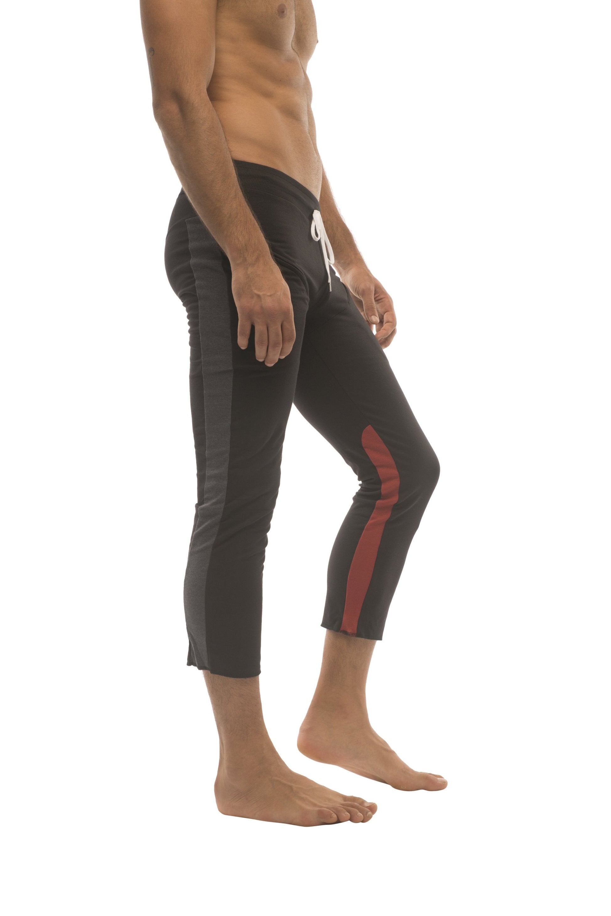 Mens black capri yoga pants with red side stripe and white drawstring waistband featuring zipper pockets