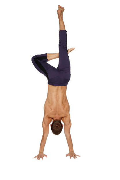 A man performing a handstand wearing dark navy mens 4/5 zipper pocket capri yoga pants for athletic use