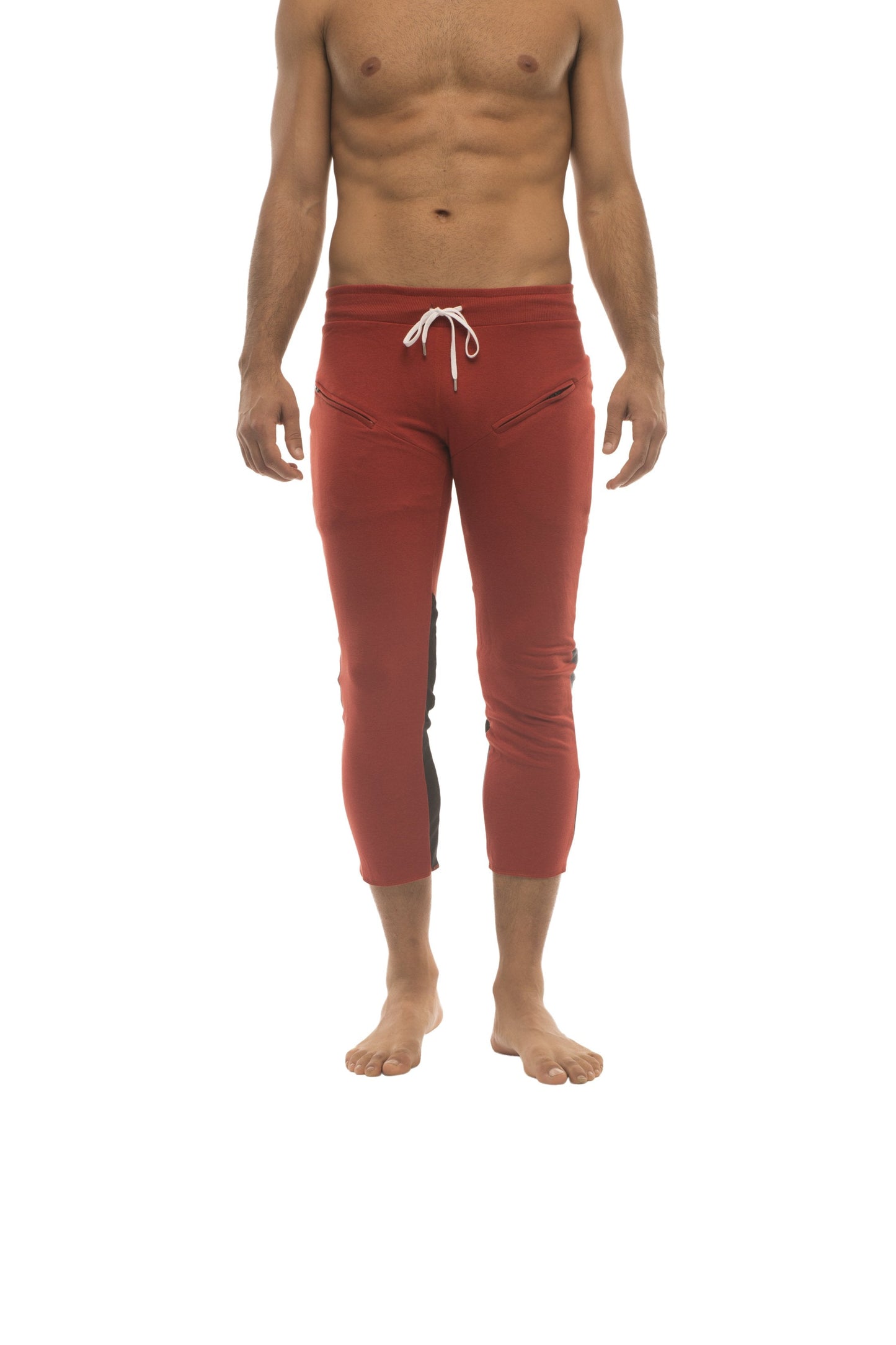 Mens red capri yoga pants with white drawstring waistband and black side panels featuring zipper pockets