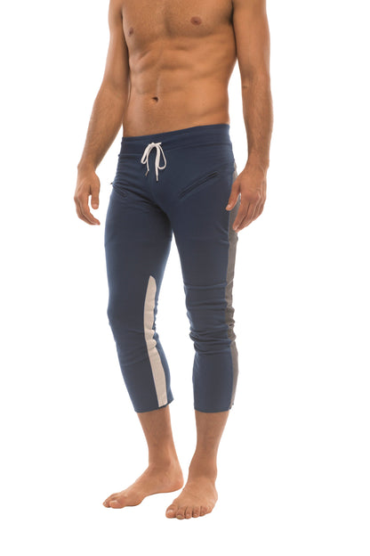 Mens navy blue athletic capri yoga pants with white side stripes and drawstring waistband featuring zipper pockets