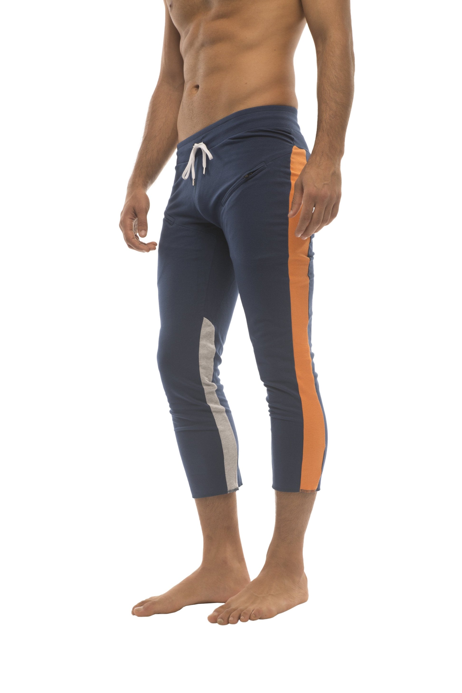 Mens navy blue athletic capri yoga pants with orange and white side stripes and zippered pockets for active wear