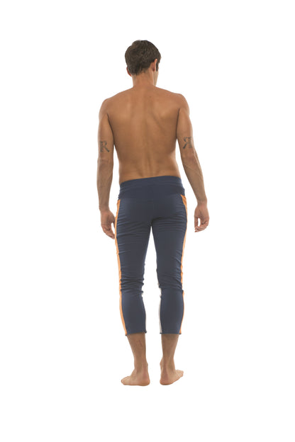 Mens navy blue capri yoga pants with orange side stripes and 4 zipper pockets for versatile activewear use