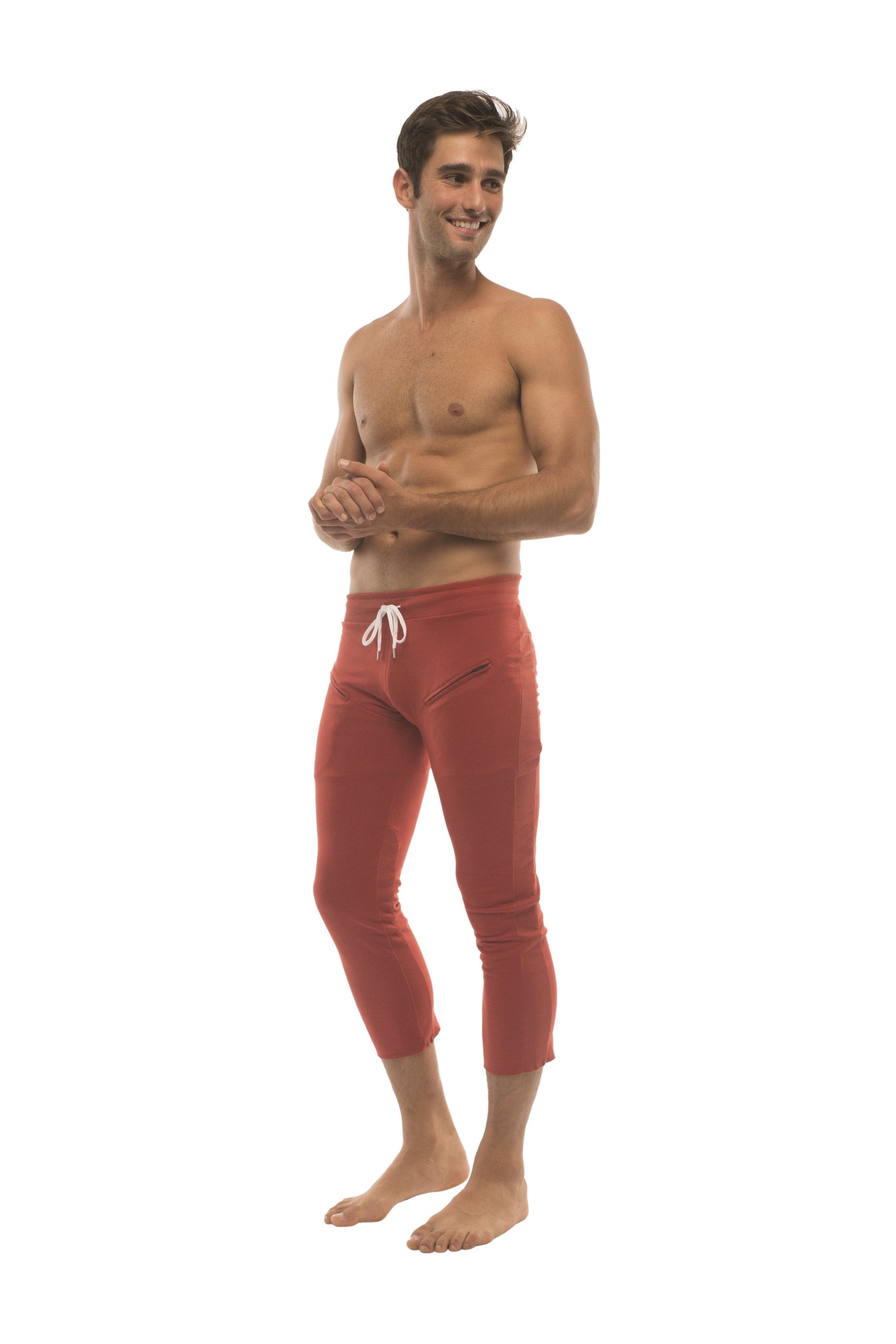 Mens cinnabar red capri yoga pants with white drawstring waistband and side zipper pockets for athletic use