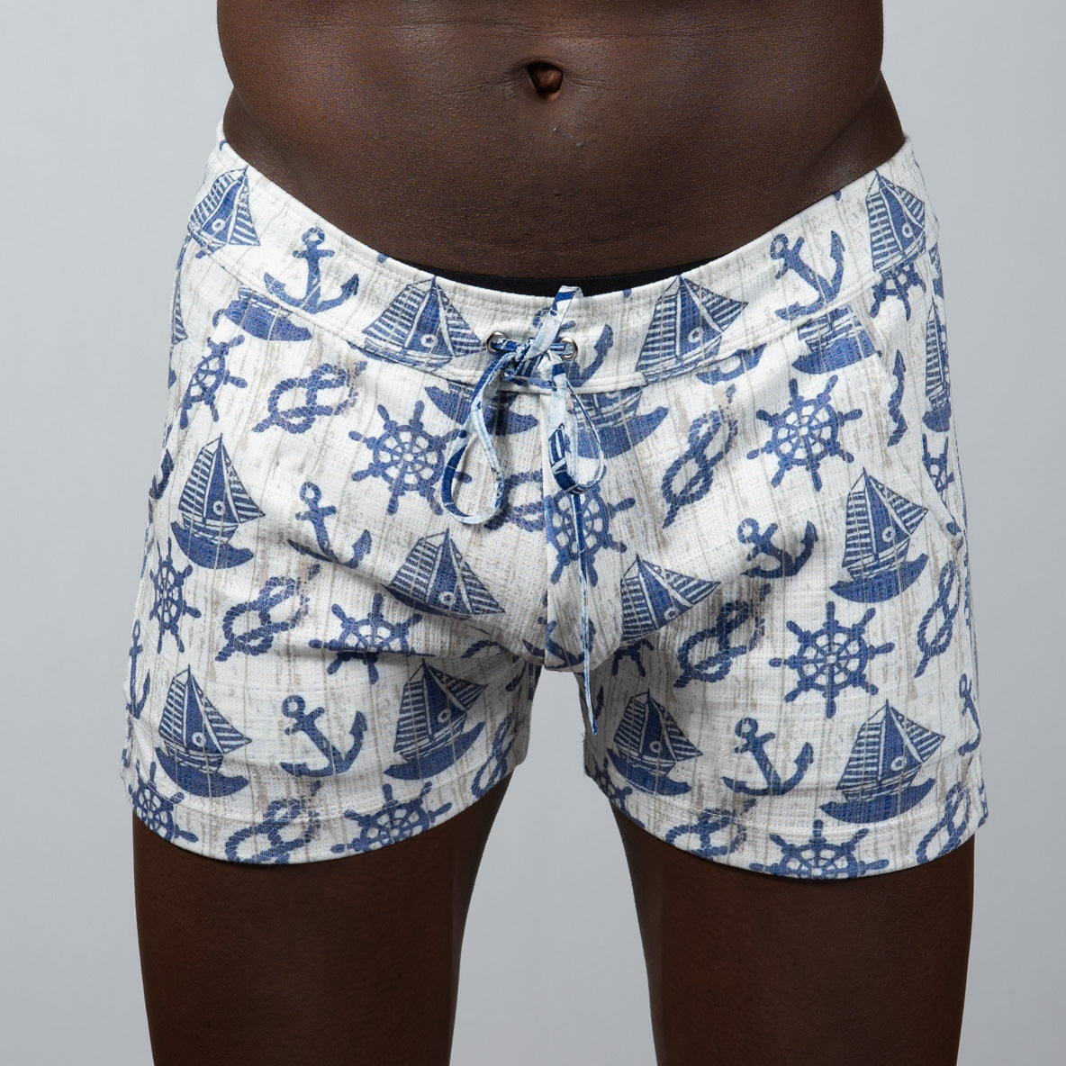 White linen texture shorts with blue nautical pattern of anchors sailboats and ship wheels in swim trunks style