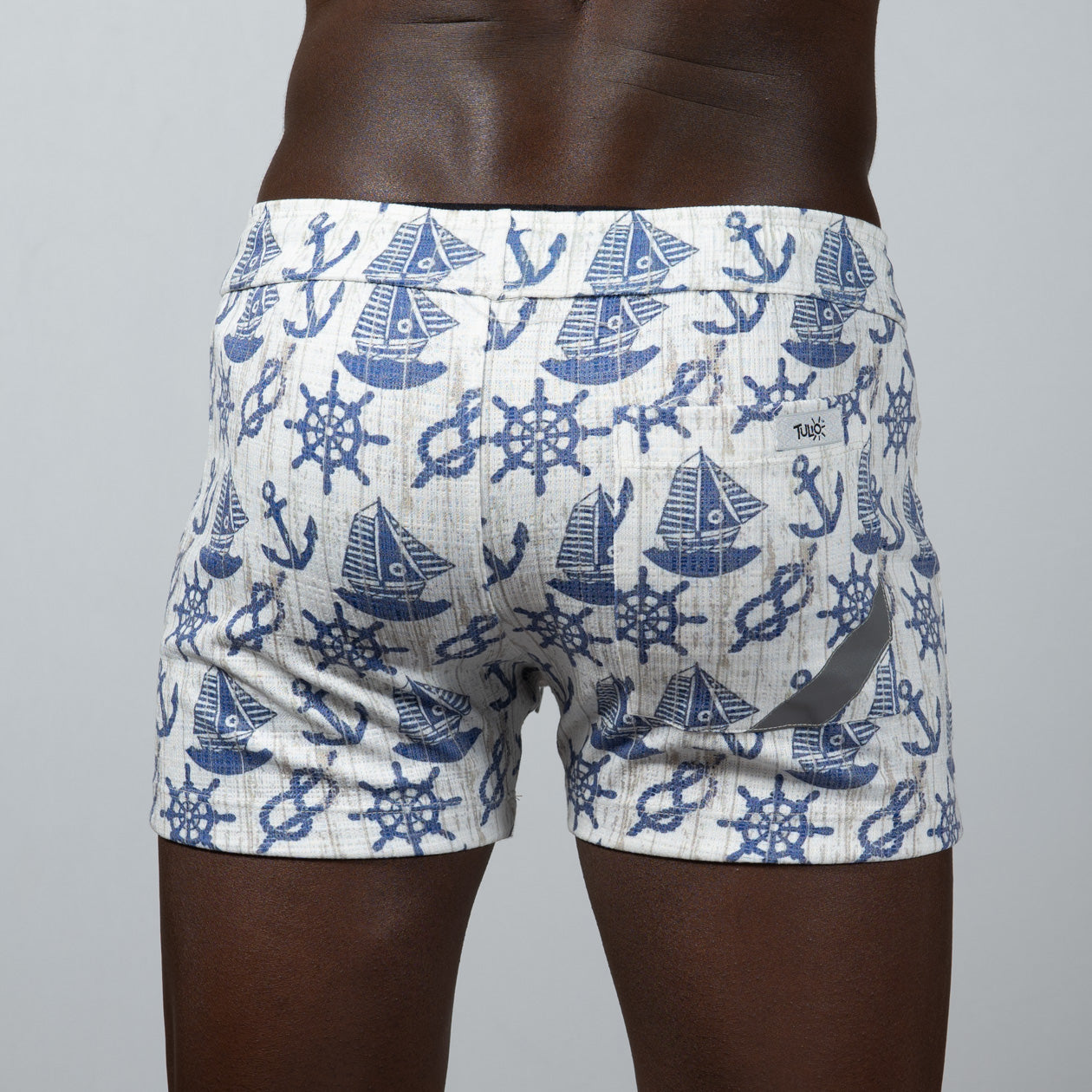 White nautical linen texture shorts featuring a navy blue pattern of sailboats anchors and ship wheels